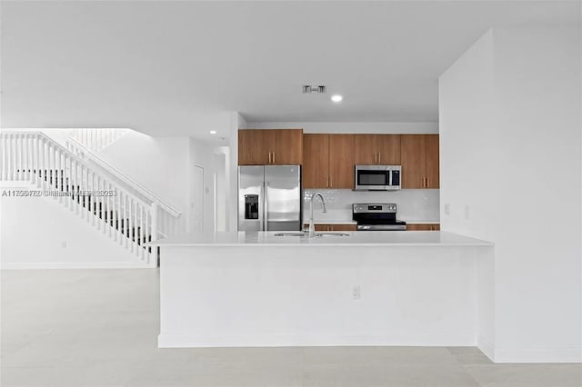 kitchen with stainless steel appliances, a sink, visible vents, light countertops, and brown cabinets