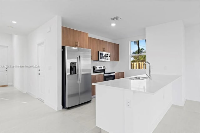 kitchen with visible vents, brown cabinetry, stainless steel appliances, light countertops, and a sink