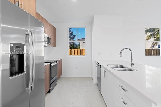 kitchen featuring stainless steel appliances, a healthy amount of sunlight, light countertops, and a sink