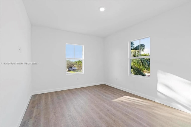 unfurnished room with recessed lighting, wood finished floors, and baseboards