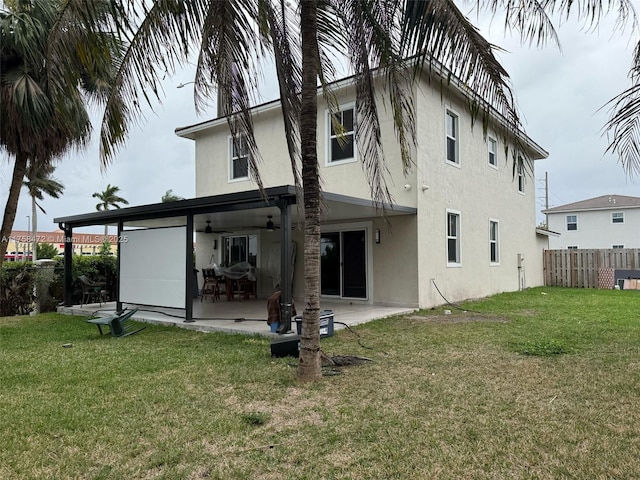 rear view of property with fence, a lawn, and stucco siding