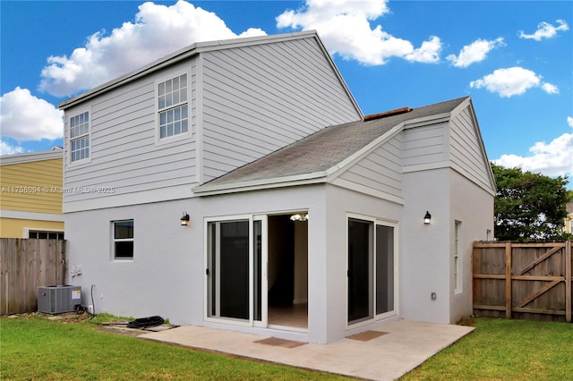 back of property with central AC unit, fence, a yard, stucco siding, and a patio area