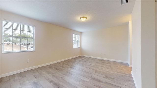 unfurnished room featuring visible vents, light wood-type flooring, and baseboards