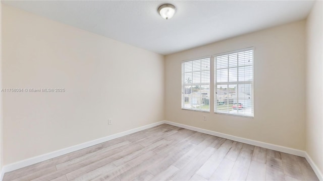 unfurnished room featuring baseboards and light wood finished floors