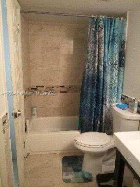 bathroom with toilet, shower / tub combo, and vanity