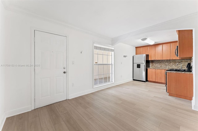 kitchen with stainless steel appliances, ornamental molding, light wood-style flooring, and tasteful backsplash