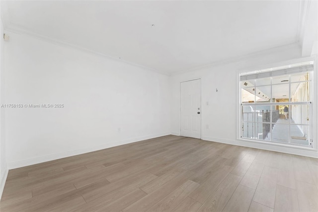 spare room with ornamental molding, light wood-style flooring, and baseboards