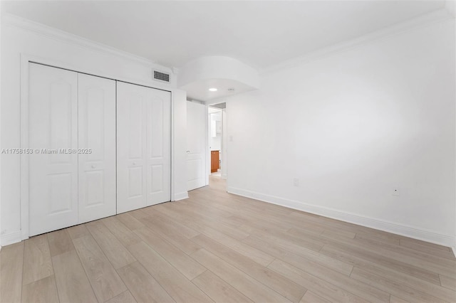 unfurnished bedroom with ornamental molding, a closet, visible vents, and light wood-style floors