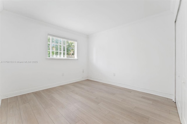 spare room featuring ornamental molding, baseboards, and light wood-type flooring
