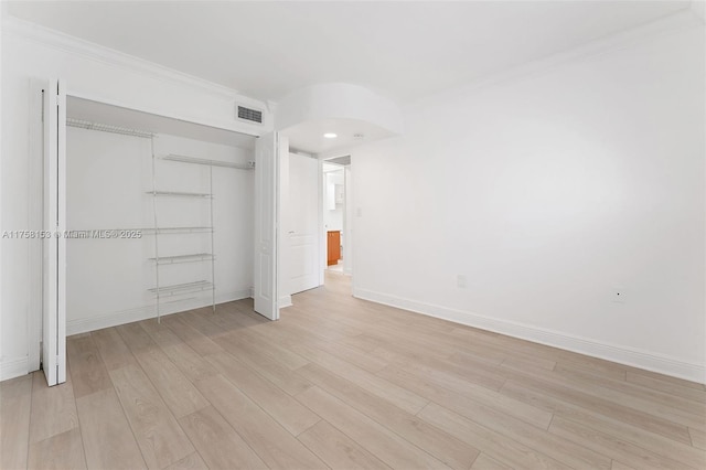 unfurnished bedroom featuring crown molding, a closet, baseboards, visible vents, and light wood-style floors
