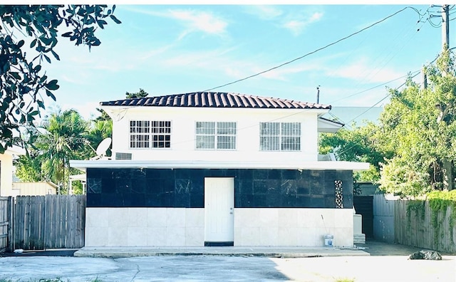 view of front of property featuring a tile roof and fence