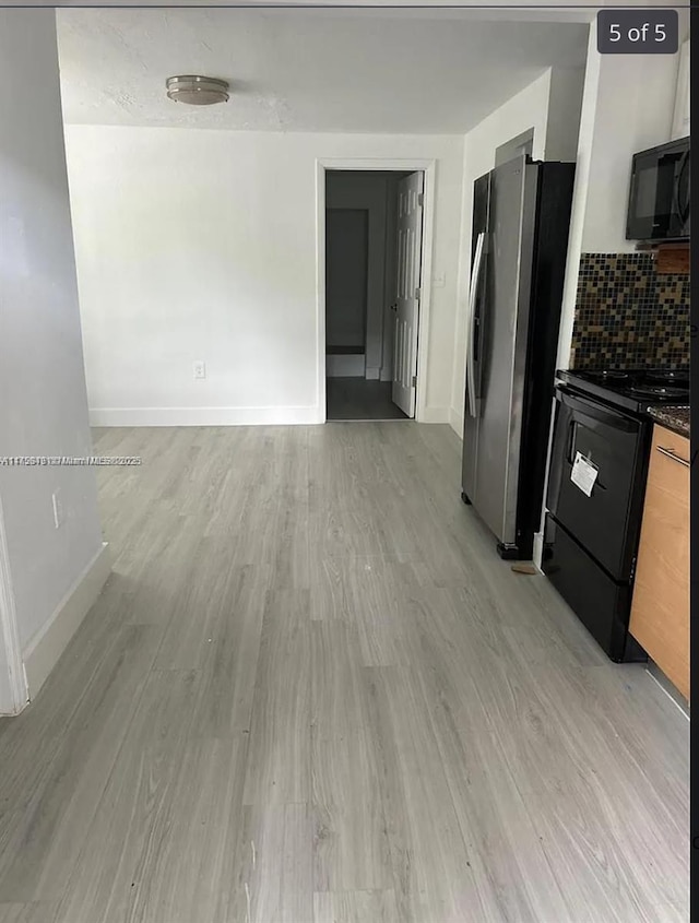 kitchen featuring dark countertops, decorative backsplash, light wood-style floors, black appliances, and baseboards