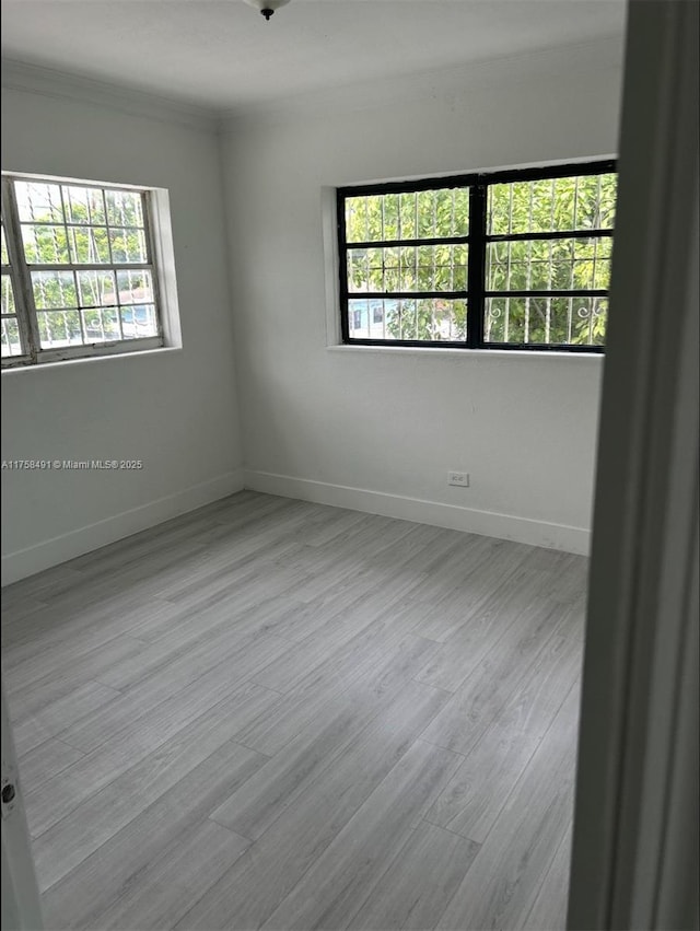 empty room with ornamental molding, baseboards, and wood finished floors