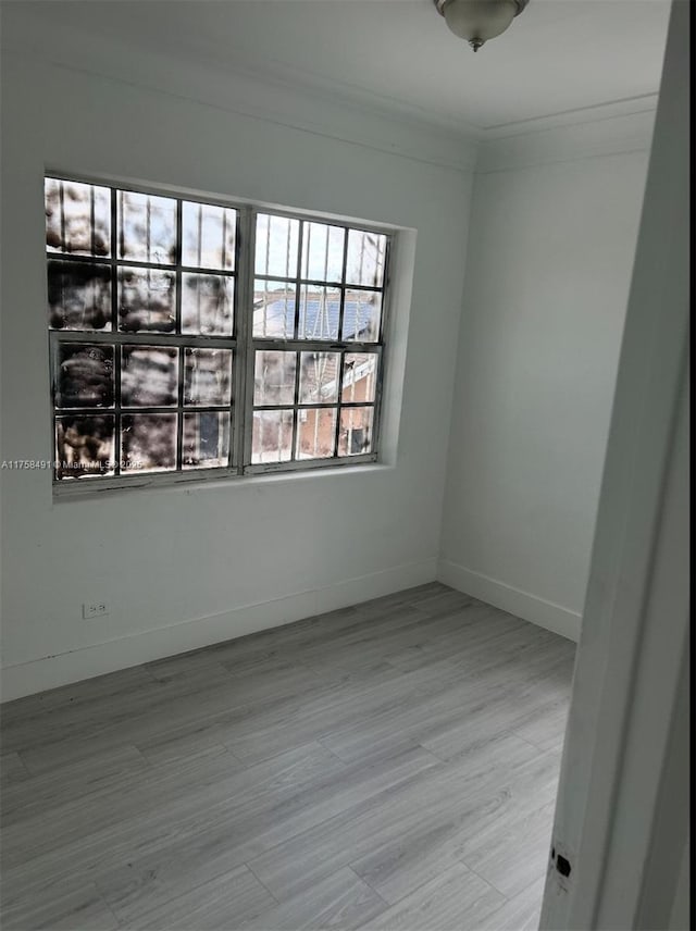 empty room with baseboards, ornamental molding, and wood finished floors