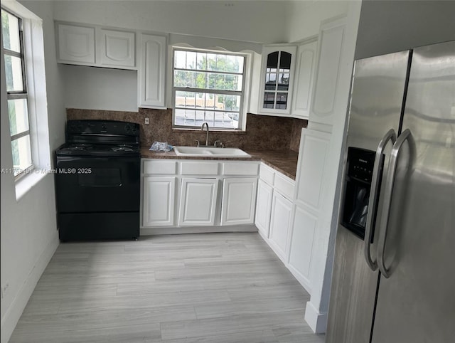 kitchen with a sink, dark countertops, stainless steel fridge, and black electric range oven