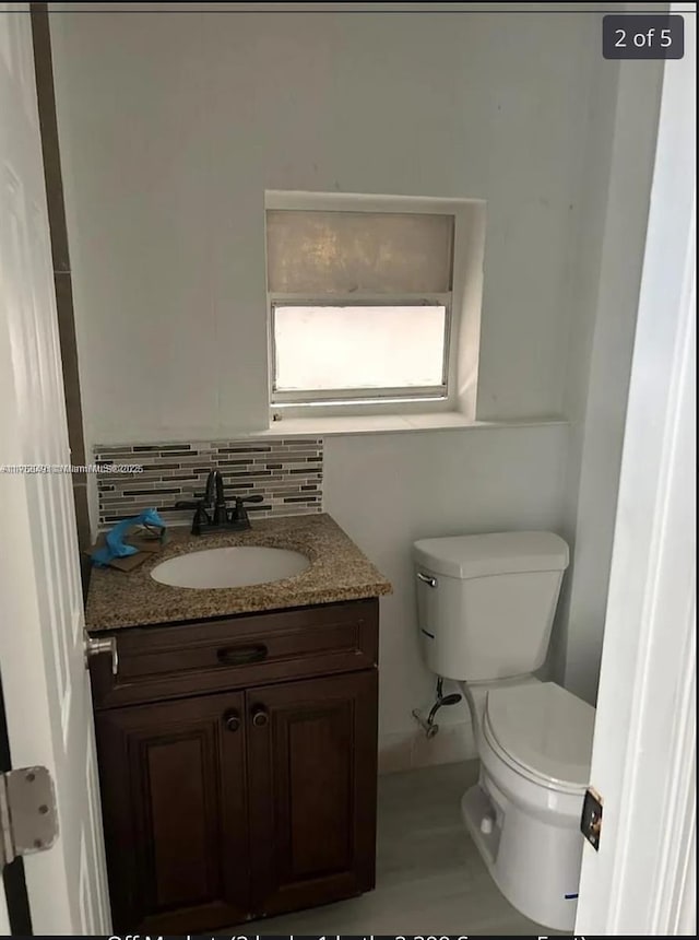 bathroom with toilet, decorative backsplash, and vanity