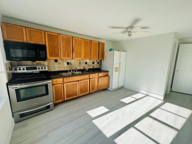 kitchen with black microwave, electric range, white refrigerator with ice dispenser, a sink, and dark countertops