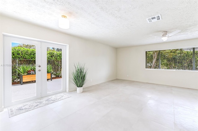 unfurnished room with a ceiling fan, french doors, visible vents, and a textured ceiling