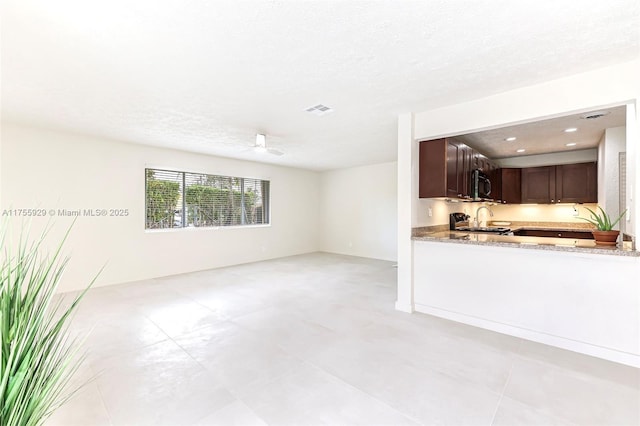 unfurnished living room featuring a textured ceiling, ceiling fan, and visible vents