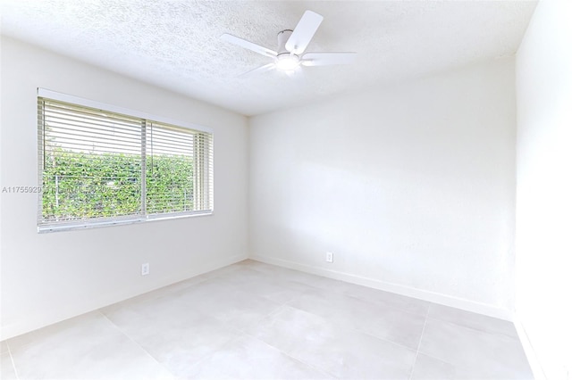 empty room featuring a textured ceiling, ceiling fan, and baseboards