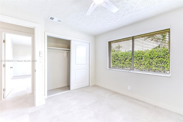 unfurnished bedroom featuring a textured ceiling, ceiling fan, visible vents, baseboards, and a closet