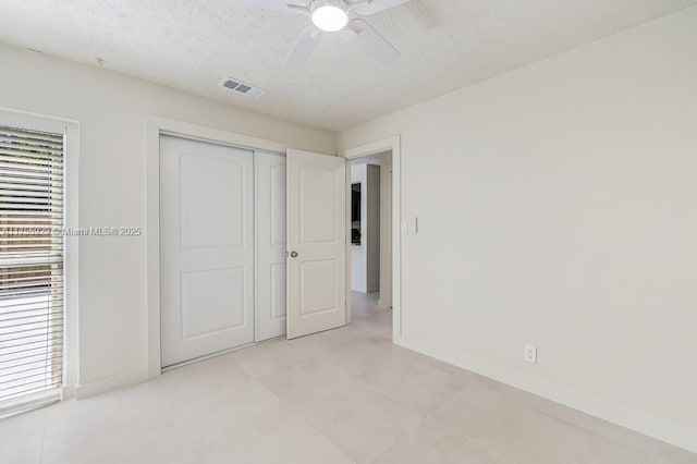 unfurnished bedroom with a closet, visible vents, a textured ceiling, and baseboards