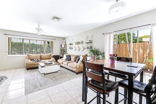 living room featuring light tile patterned floors, ceiling fan, visible vents, and baseboards