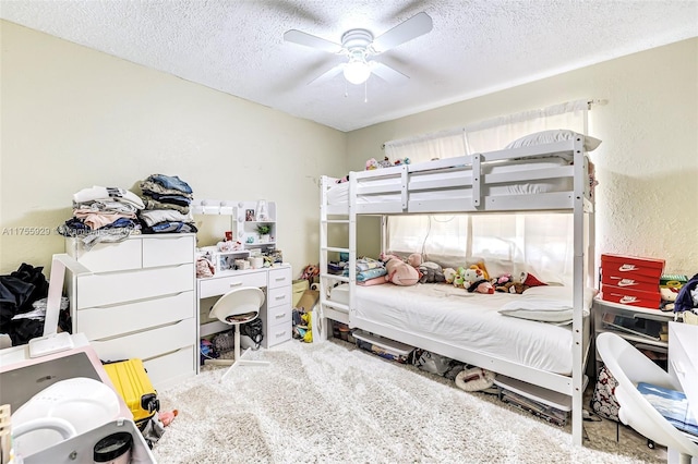 bedroom featuring a ceiling fan, carpet, a textured wall, and a textured ceiling