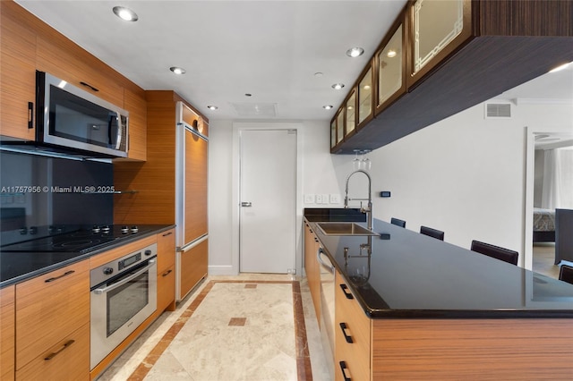 kitchen with stainless steel appliances, dark countertops, recessed lighting, a sink, and modern cabinets