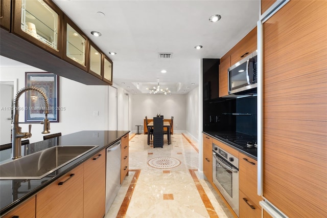 kitchen featuring baseboards, visible vents, dark countertops, appliances with stainless steel finishes, and a sink