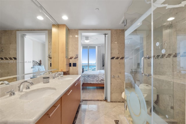 ensuite bathroom with tile walls, a sink, a shower stall, and ensuite bathroom