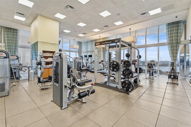 exercise room with a wall of windows, a paneled ceiling, and visible vents