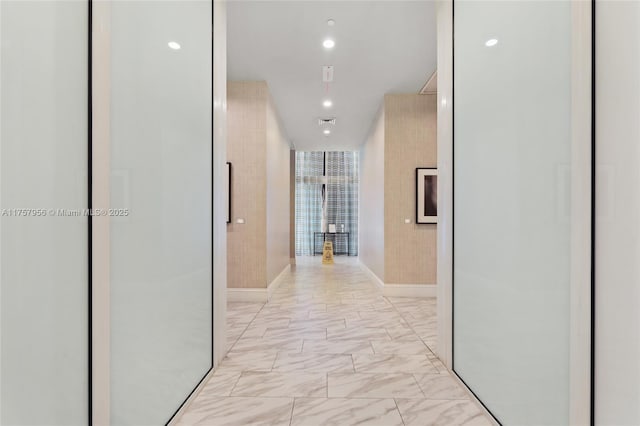 corridor featuring marble finish floor, visible vents, floor to ceiling windows, and recessed lighting