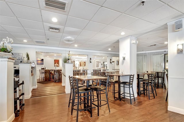 dining room featuring visible vents, a drop ceiling, baseboards, and wood finished floors