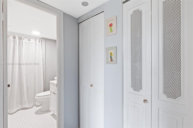 full bath with tile patterned flooring, toilet, vanity, a closet, and a shower with curtain