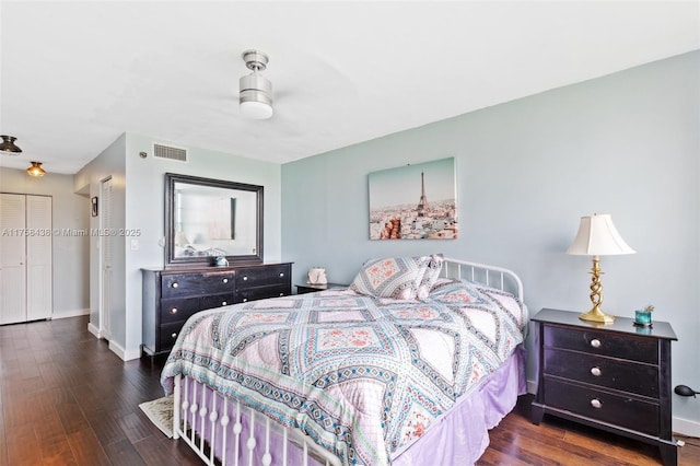 bedroom with baseboards, visible vents, and wood finished floors