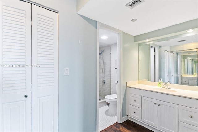 bathroom featuring visible vents, wood finished floors, vanity, a shower stall, and a closet