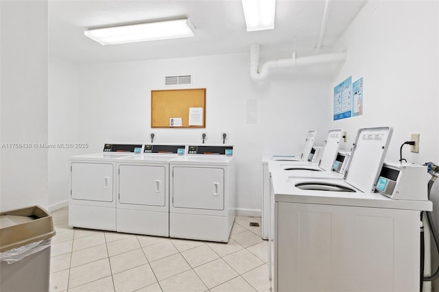 community laundry room with washing machine and dryer, visible vents, baseboards, and light tile patterned floors