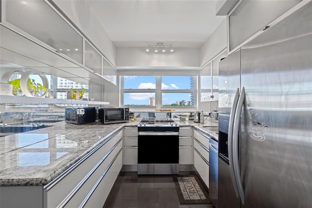 kitchen with modern cabinets, appliances with stainless steel finishes, white cabinets, and light stone counters