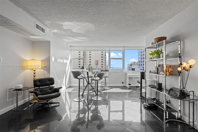 tiled home office featuring a textured ceiling, a view of city, visible vents, and baseboards