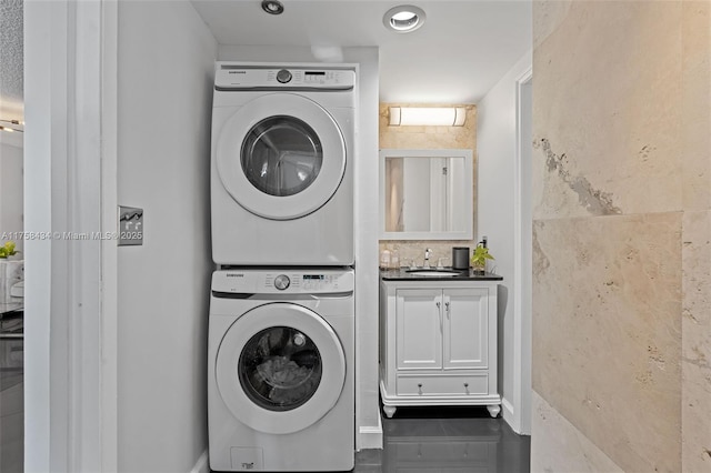 washroom with laundry area, stacked washing maching and dryer, and a sink