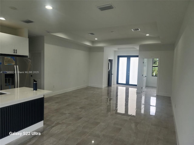 empty room featuring french doors, a tray ceiling, and visible vents