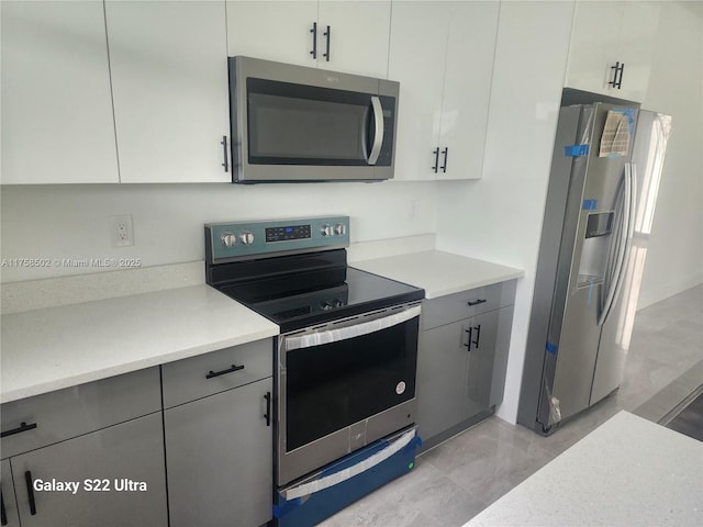 kitchen with stainless steel appliances, light countertops, white cabinets, and gray cabinetry