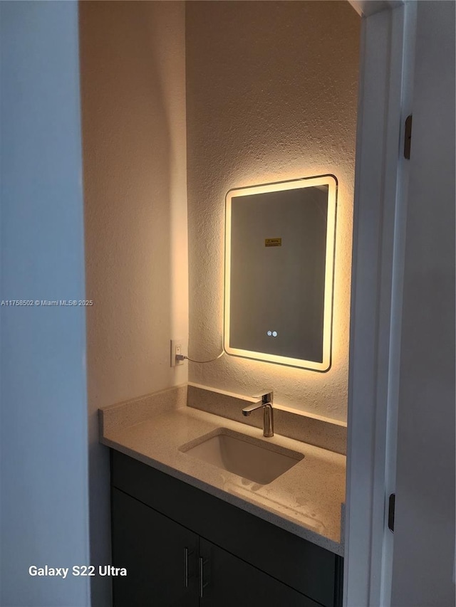 bathroom featuring a textured wall and vanity