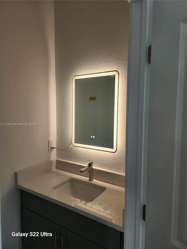 bathroom with a textured wall and vanity