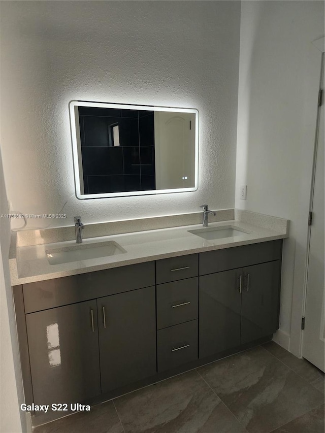 bathroom with double vanity, a sink, and a textured wall