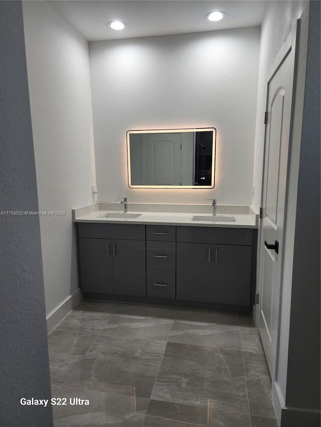 bathroom featuring double vanity, a sink, and baseboards