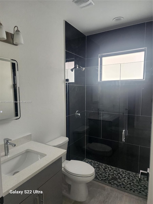 bathroom featuring a stall shower, visible vents, vanity, and toilet