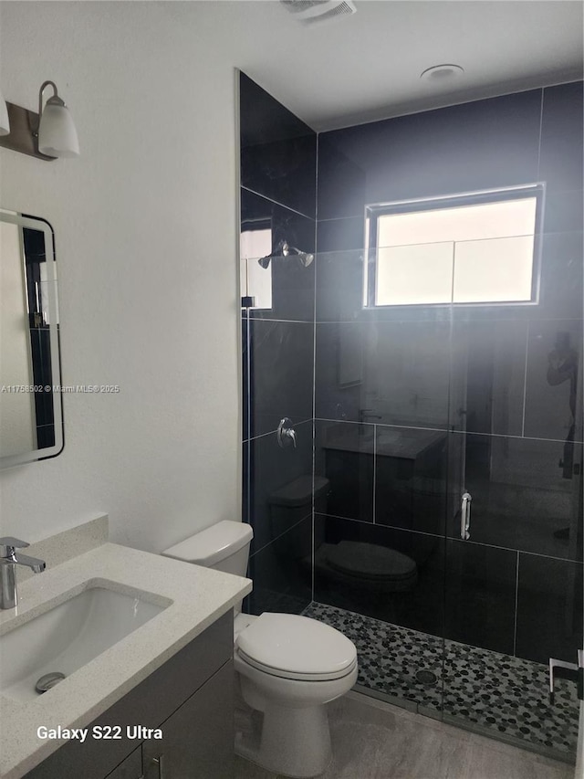 full bath featuring visible vents, a stall shower, vanity, and toilet