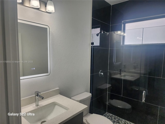 full bathroom with toilet, a textured wall, a shower stall, and vanity